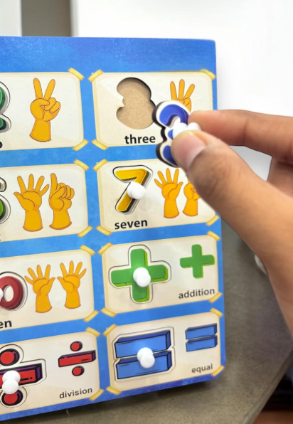Child's hand lifting the number 3 piece by its wooden knob